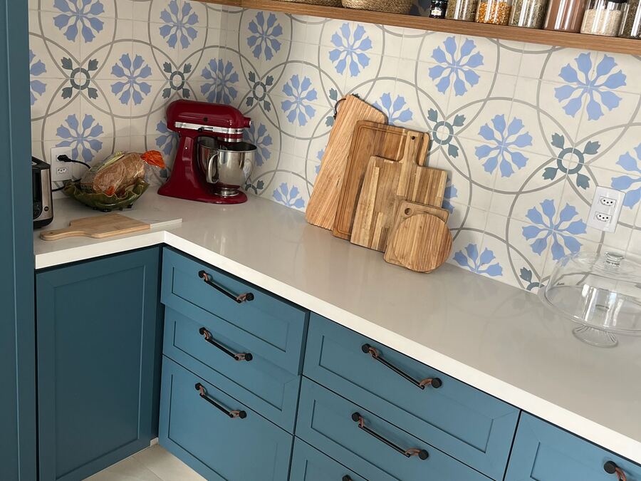 Bancada em pedra clara com azulejo decorado ao fundo